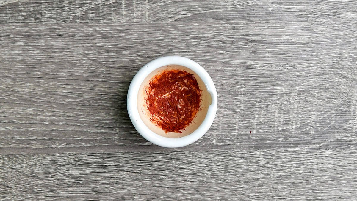 Saffron strips in a small white mortar crushed to release it essential oil.