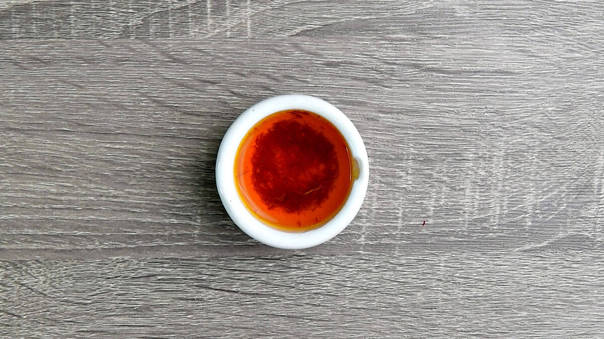 Hot water added to the crushed saffron in mortar pestle to bloom.