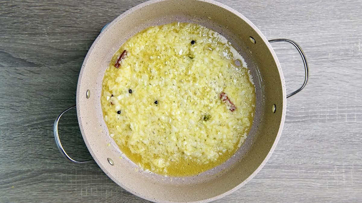 Diced onions cooking in the skillet together with warm spices in butter and olive oil.