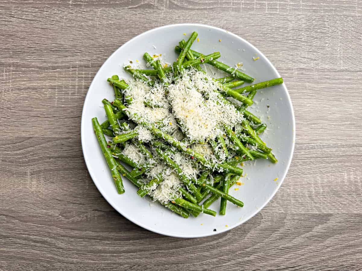 The seasoned green beans now topped with parmesan cheese and then mixed together.