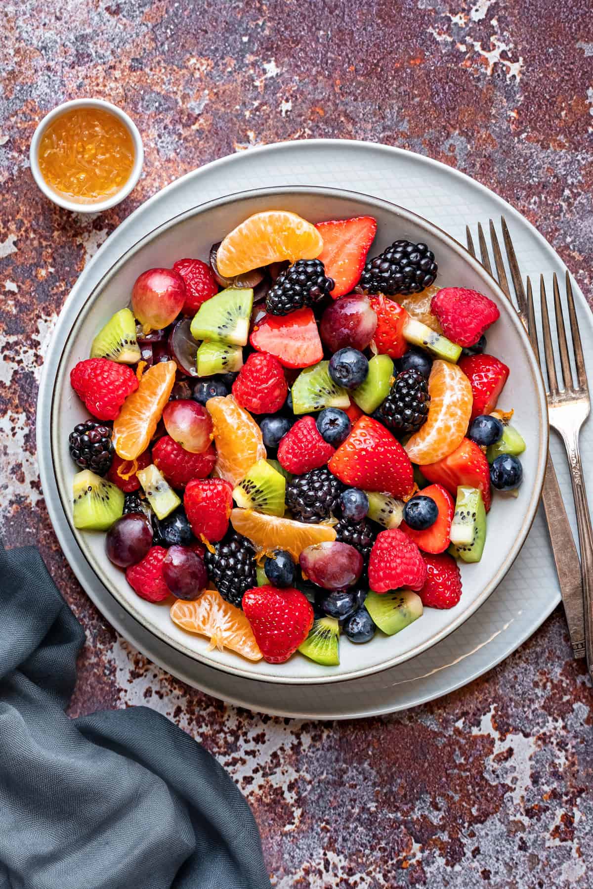 Berry fruit salad with a glazed dressing made of orange juice, lime juice, and maple syrup, inside a bowl and ready to be served.
