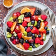 Berry fruit salad with a glazed dressing made of orange juice, lime juice, and maple syrup, inside a bowl and ready to be served.