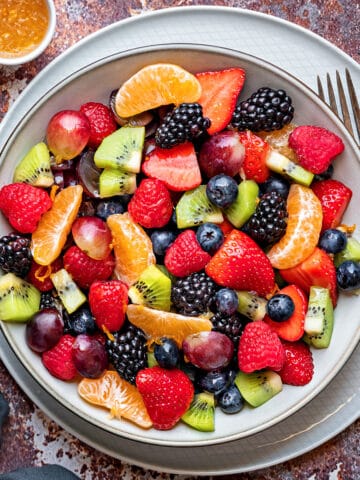 Berry fruit salad with a glazed dressing made of orange juice, lime juice, and maple syrup, inside a bowl and ready to be served.