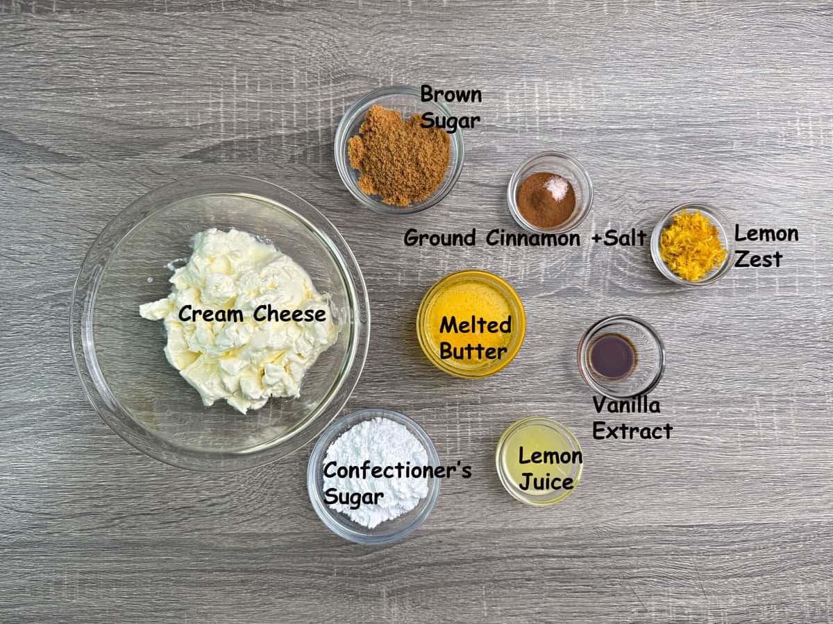 Ingredients in a bowl for the cheesecake topping that includes, cream cheese, sugar, ground cinnamon, salt, vanilla, lemon zest, lemon juice, and melted butter.