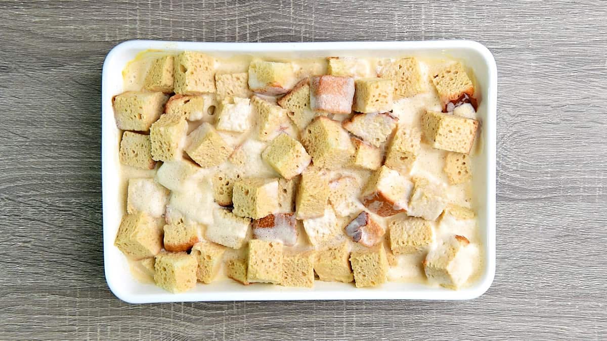 The egg and cream mixture poured over the brioche bread cubes in the 9x13 baking pan.