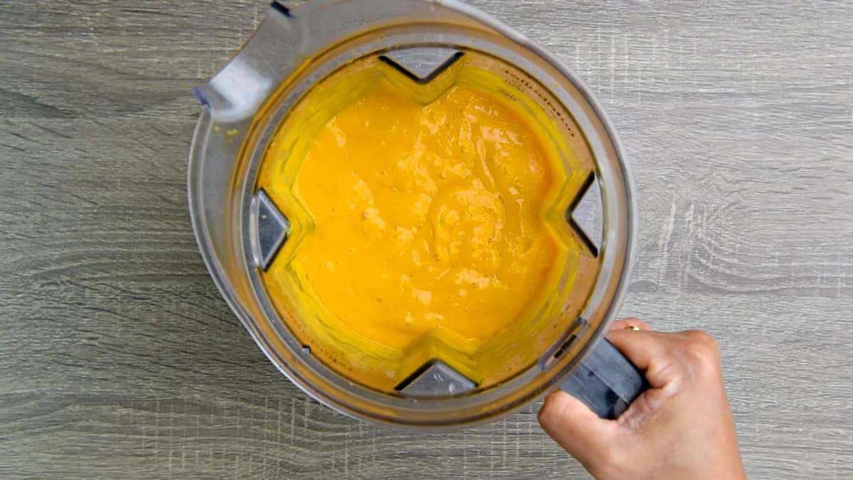 Mango lime, and yogurt mixture blended together smooth inside a high speed blender.