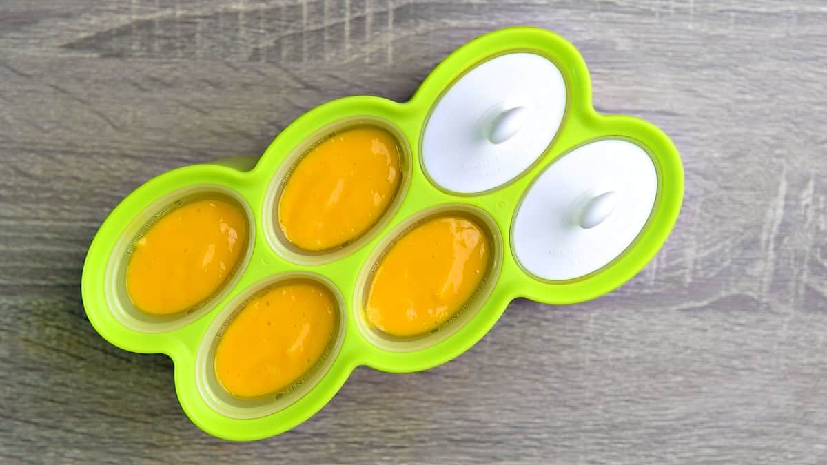 Mango mixture poured into a popsicle mold and topped with lid to be placed in a freezer.