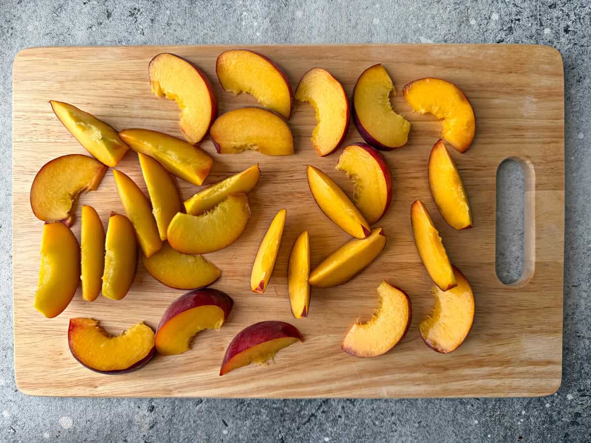 Peaches sliced on a wooden cutting board for salad.