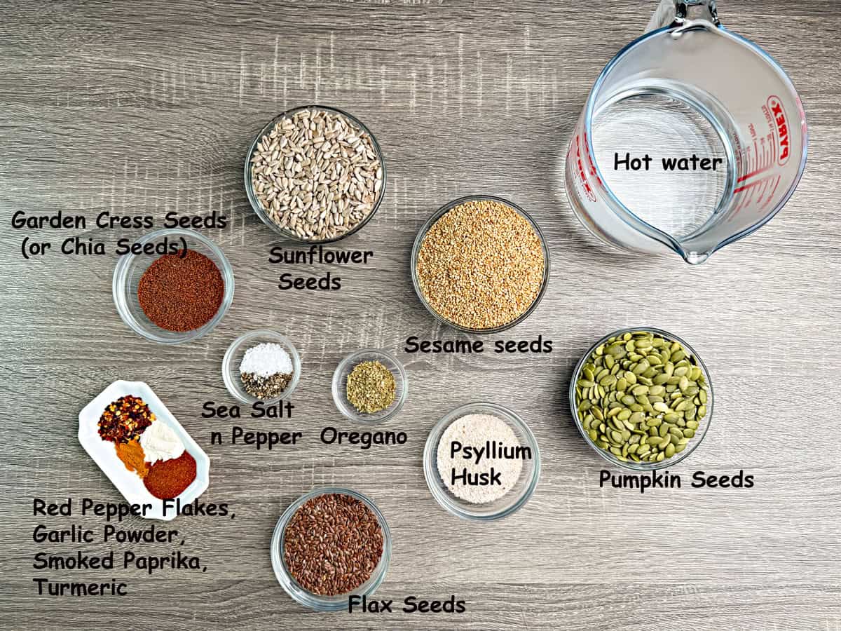 Recipe ingredients in bowls that include sesame seeds, sunflower seeds, pumpkin seeds, flax seeds, chia seeds, hot water and seasonings.