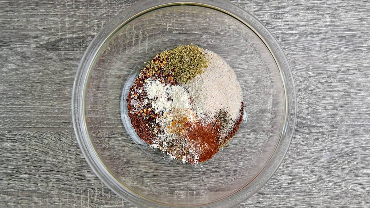 ground flaxseed meal, chia seeds, psyllium husk, oregano, pepper, paprika and more added and mixed into a glass bowl.