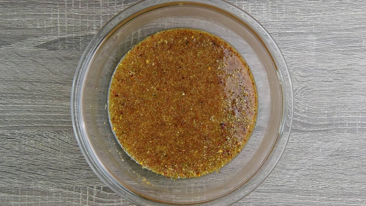 Hot water added to the flaxseed meal and spices within the glass bowl to create a gelatinous mixture.