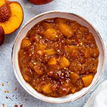 Top-down view of peach chutney in a serving bowl with red pepper flakes dusted on top.