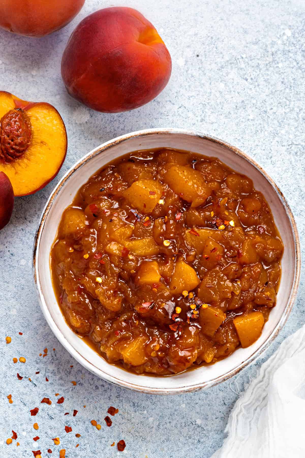 Top-down view of peach chutney in a serving bowl with red pepper flakes dusted on top.