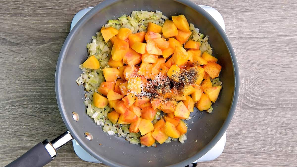 Peaches were added to the sautéed onion and mixed with salt and pepper in the pan.