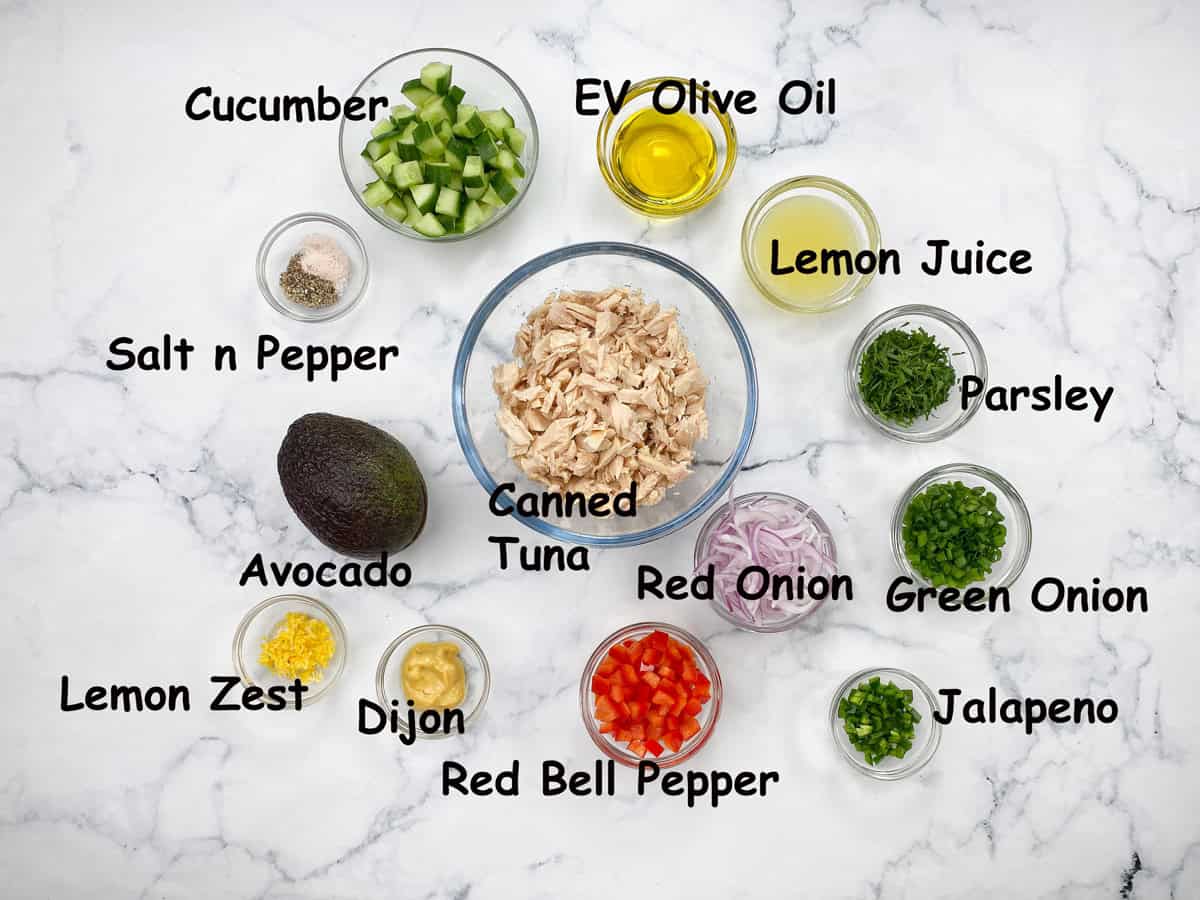 recipe Ingredients in bowls for salad that include tuna, lemon juice, cucumber, avocado, Dijon, fresh herbs, extra virgin olive oil, jalapeño and onion.