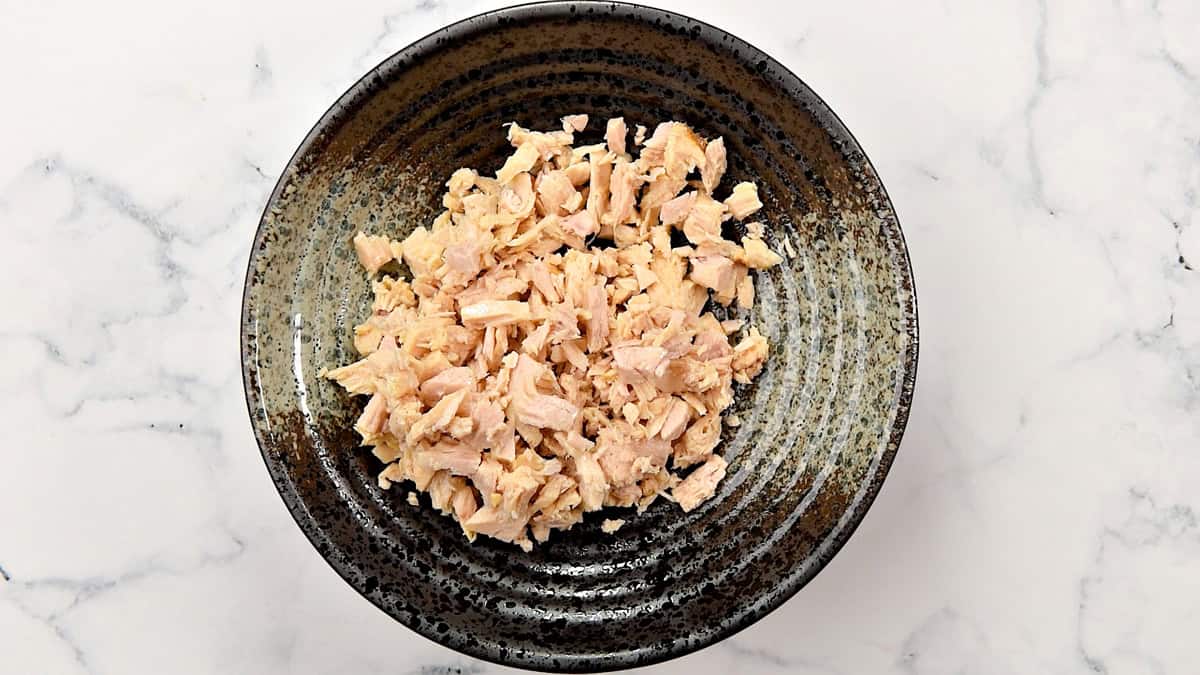 Shredded, drained and flaked tuna in a large bowl.