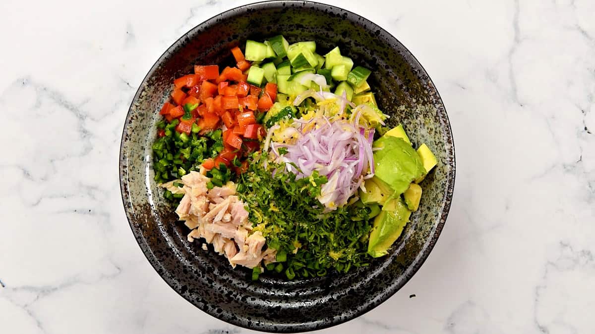 Avocado, onions, cucumber, red bell peppers, jalapeños, parsley, scallion added to the bowl with tuna.