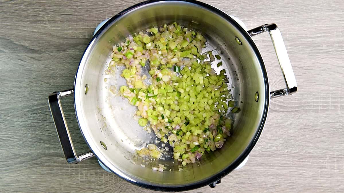 Celery added to the sautéed shallots and scallions inside the soup pot.