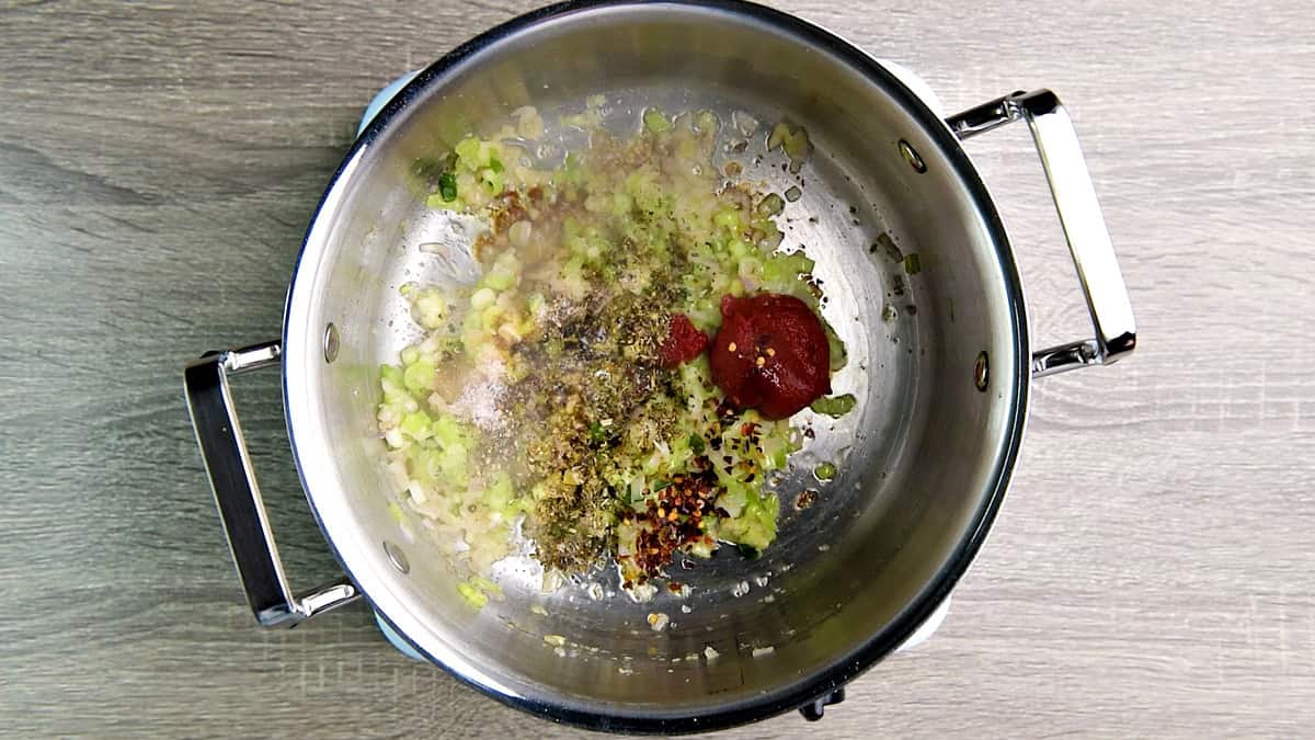 Spices that include tomato paste, salt, pepper, dried herbs, and soy sauce added to the pot.