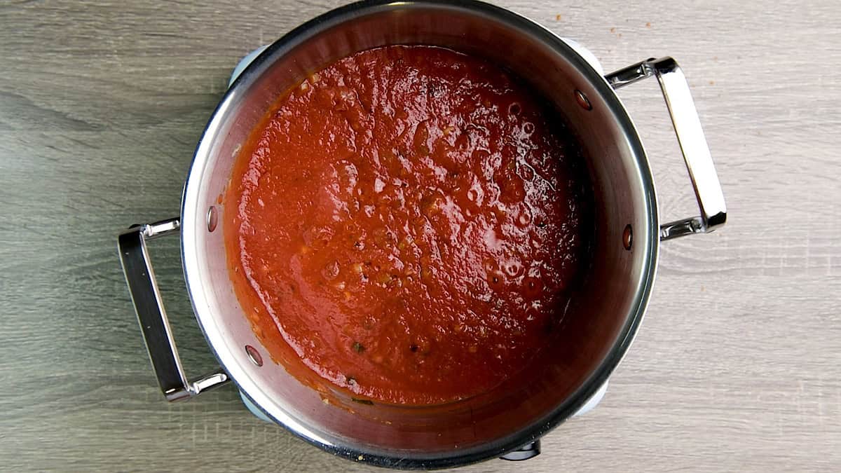 Tomato sauce and vegetable stock added to the mix of veggies and spices inside the pot to boil.